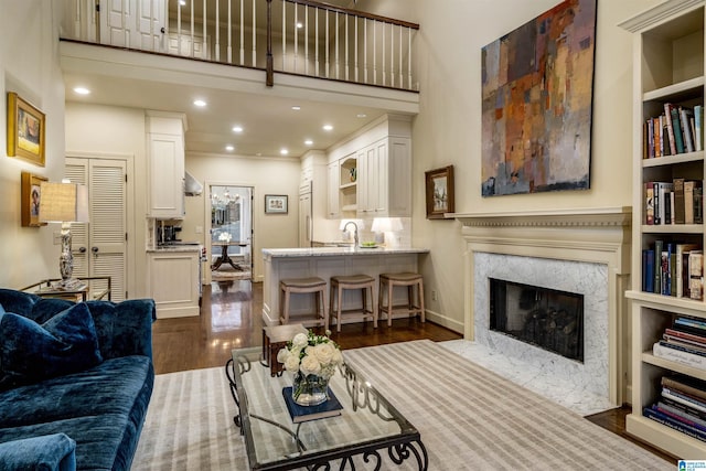 living area featuring baseboards, a premium fireplace, dark wood finished floors, recessed lighting, and a towering ceiling