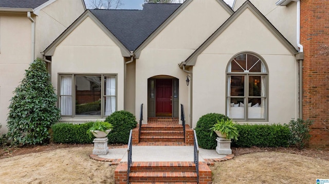 view of front of home with a shingled roof and stucco siding