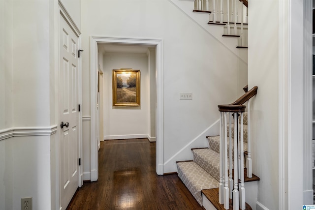 hallway with dark wood-type flooring, stairway, and baseboards