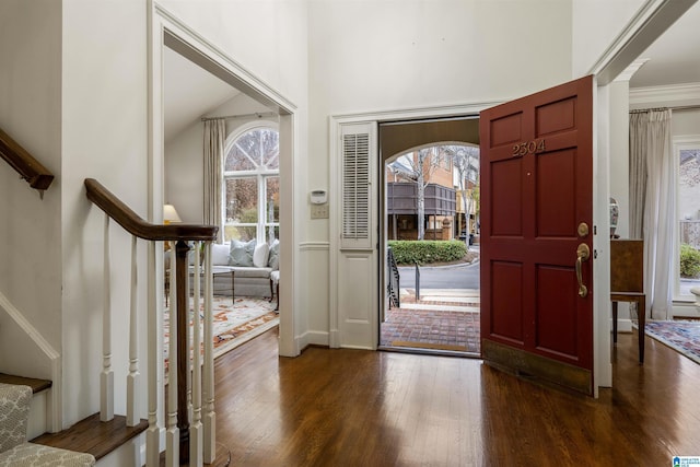 entrance foyer with dark wood finished floors, stairway, and a wealth of natural light