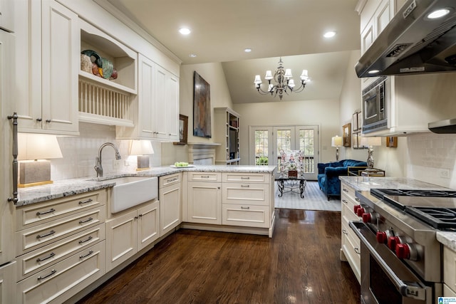 kitchen with under cabinet range hood, a sink, stainless steel appliances, a peninsula, and dark wood-style flooring