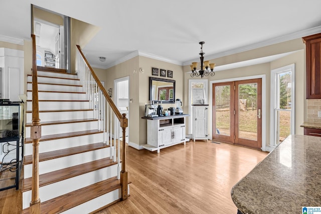 foyer entrance featuring stairs, light wood-type flooring, a notable chandelier, and crown molding