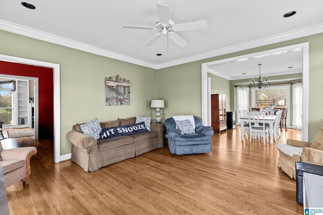 living room with ceiling fan with notable chandelier, a wealth of natural light, crown molding, and wood finished floors