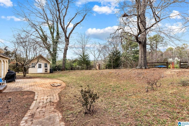 view of yard with a patio area, fence, and an outbuilding