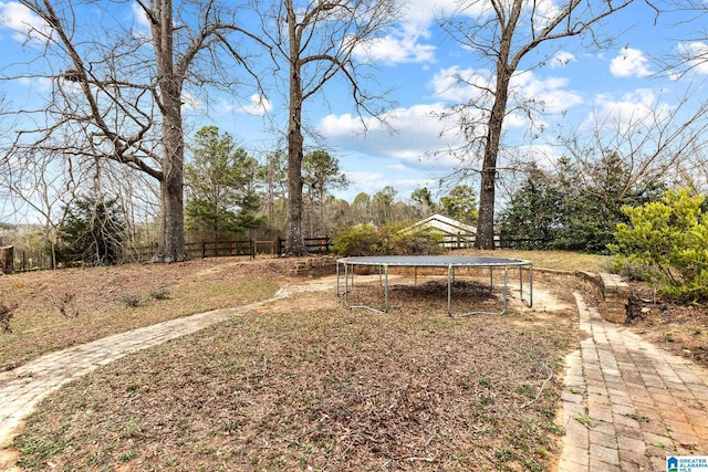 view of yard featuring a trampoline and fence