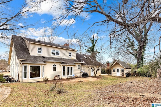 rear view of property featuring roof with shingles, a lawn, a chimney, and an outdoor structure