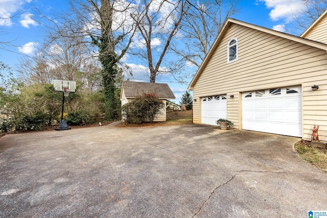 view of side of property featuring a garage, driveway, and an outbuilding