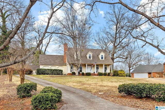 cape cod home featuring a porch, a garage, a chimney, and a front lawn