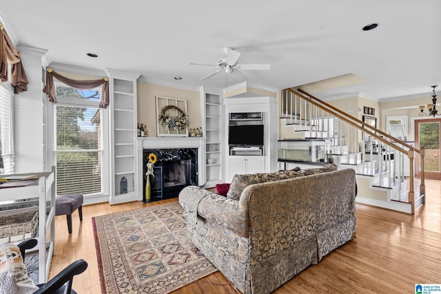 living room featuring ornamental molding, plenty of natural light, a premium fireplace, and stairs