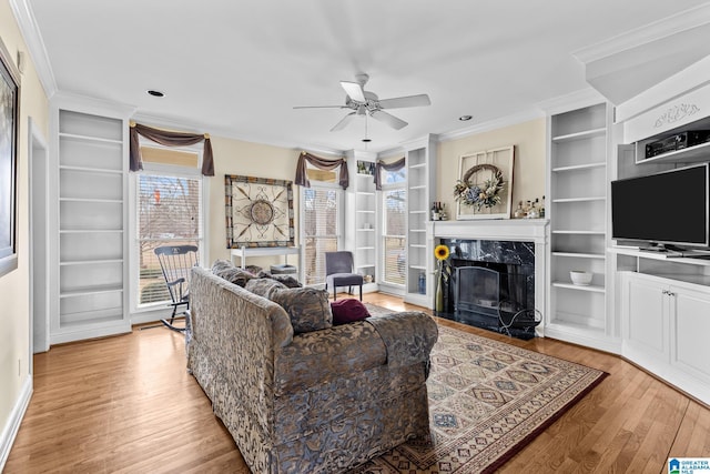 living room with ornamental molding, light wood-type flooring, a high end fireplace, and built in features