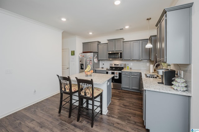 kitchen featuring a center island, visible vents, appliances with stainless steel finishes, a sink, and a kitchen bar