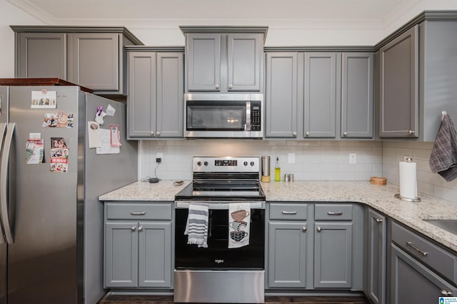 kitchen with appliances with stainless steel finishes, backsplash, light stone counters, and gray cabinetry