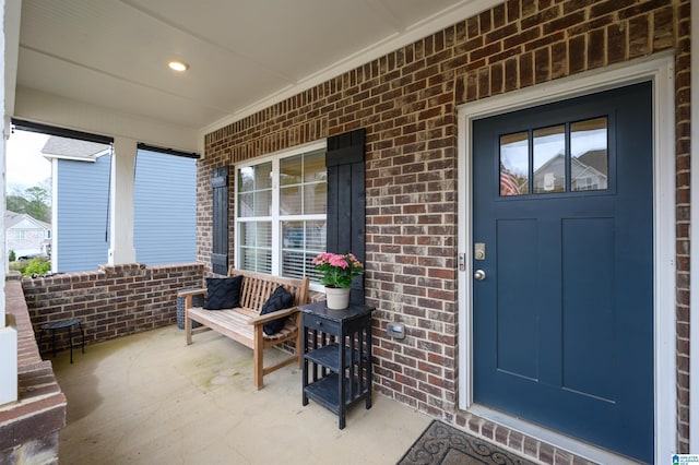 entrance to property featuring a porch and brick siding