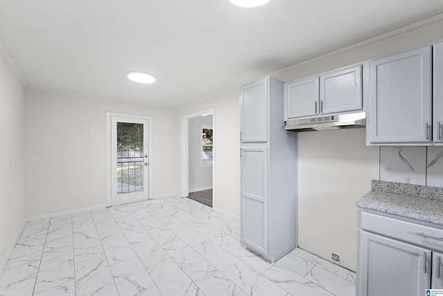 kitchen with light stone counters, marble finish floor, under cabinet range hood, and baseboards