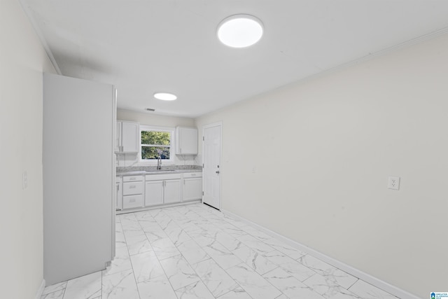 kitchen with a sink, baseboards, white cabinets, marble finish floor, and light countertops