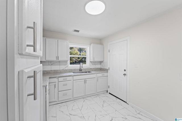 kitchen with marble finish floor, light countertops, visible vents, white cabinetry, and a sink