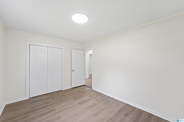 unfurnished bedroom with light wood-type flooring, a closet, and baseboards