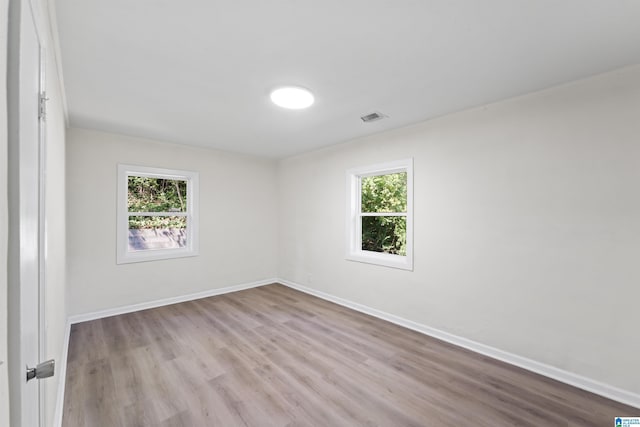 empty room featuring baseboards, visible vents, and a healthy amount of sunlight