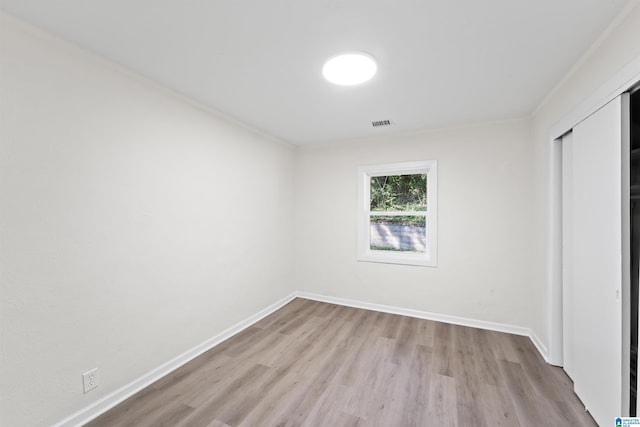 unfurnished bedroom featuring visible vents, a closet, baseboards, and wood finished floors