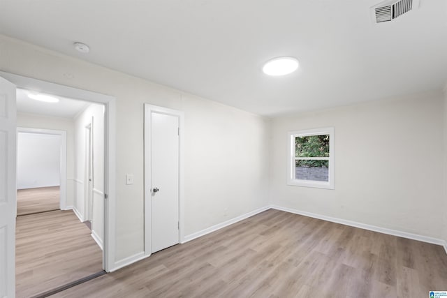 spare room featuring light wood-style floors, baseboards, and visible vents