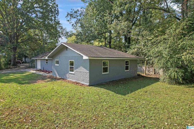 view of side of property with stucco siding and a yard