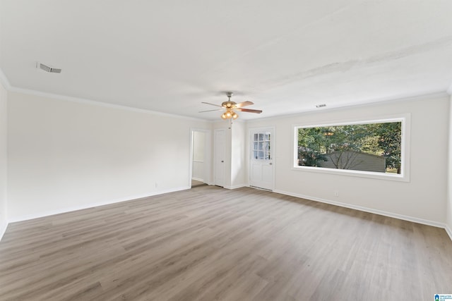 empty room with ornamental molding, wood finished floors, a ceiling fan, and baseboards