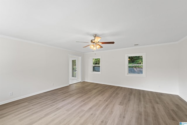 spare room with crown molding, visible vents, a ceiling fan, wood finished floors, and baseboards