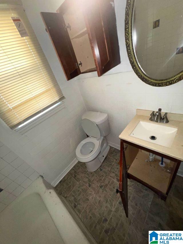 bathroom with toilet, tile walls, and vanity