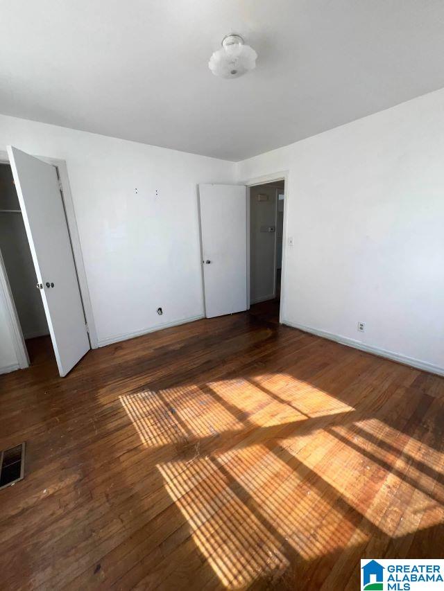 unfurnished bedroom with visible vents, baseboards, and wood finished floors