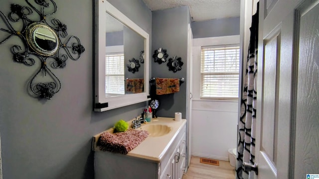 full bath with visible vents, wood finished floors, curtained shower, a textured ceiling, and vanity