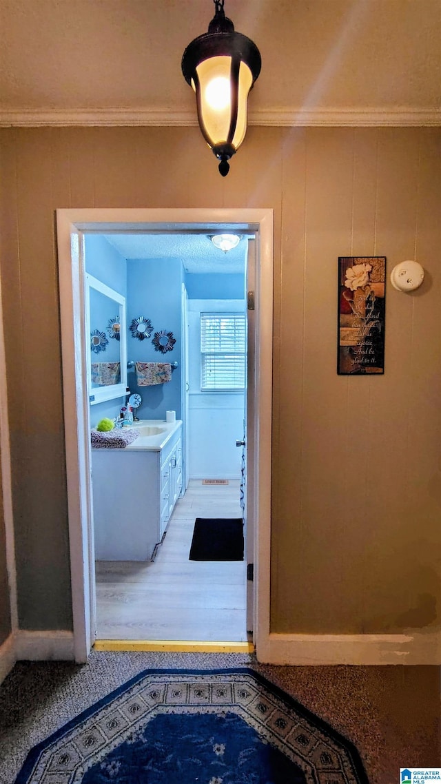 hallway featuring a sink and crown molding