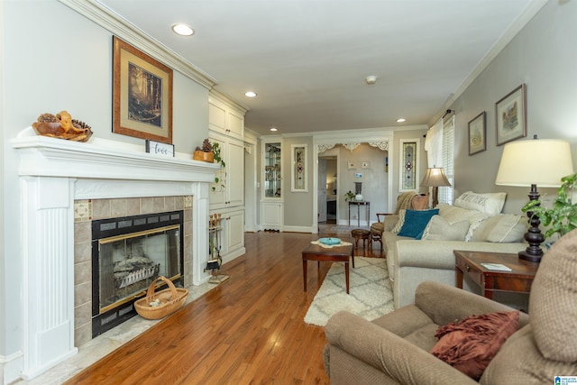 living area with recessed lighting, a fireplace, wood finished floors, and crown molding