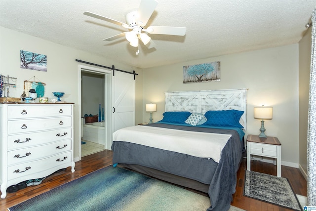 bedroom with a ceiling fan, wood finished floors, a textured ceiling, and a barn door