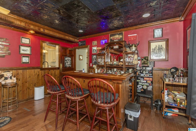 bar with a wainscoted wall, a bar, an ornate ceiling, and crown molding