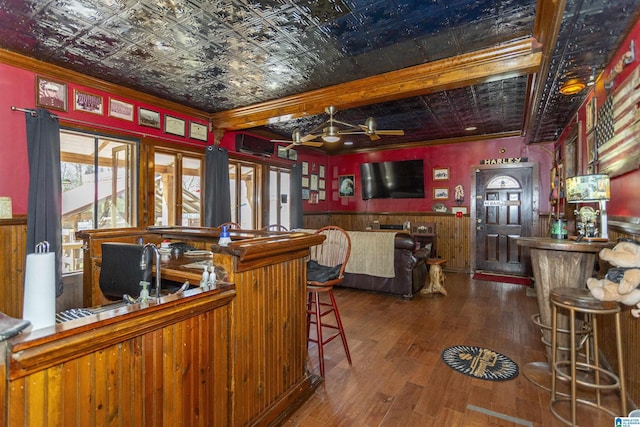 bar with a bar, an ornate ceiling, crown molding, and wood finished floors