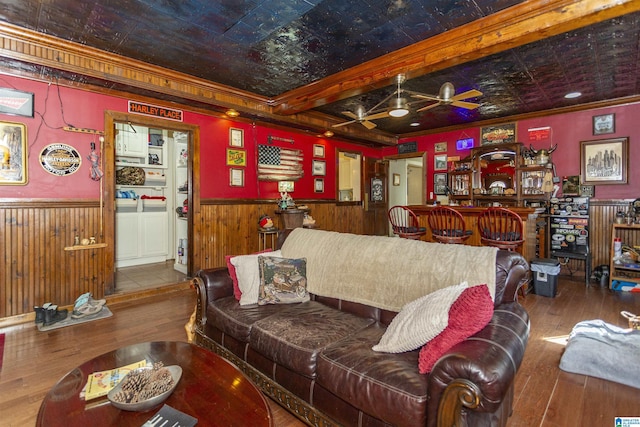 living area featuring hardwood / wood-style floors, wainscoting, an ornate ceiling, and crown molding