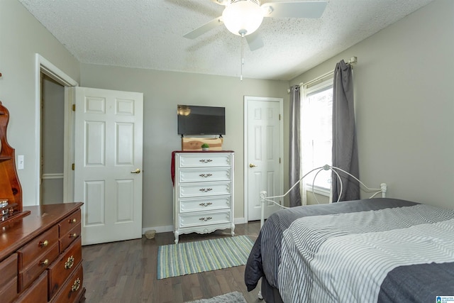 bedroom featuring a textured ceiling, dark wood-style flooring, a ceiling fan, and baseboards