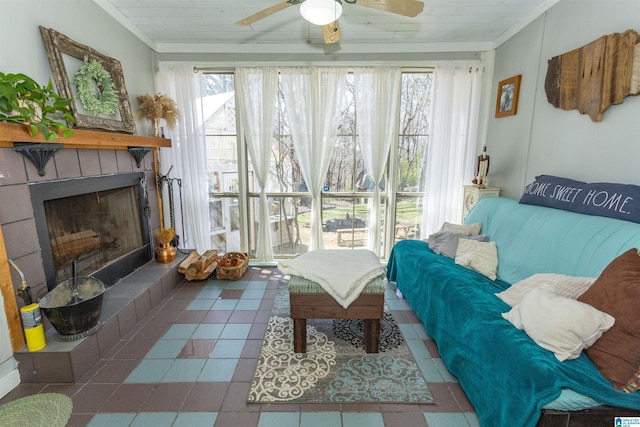 living room with ornamental molding, wooden ceiling, a tiled fireplace, and a ceiling fan