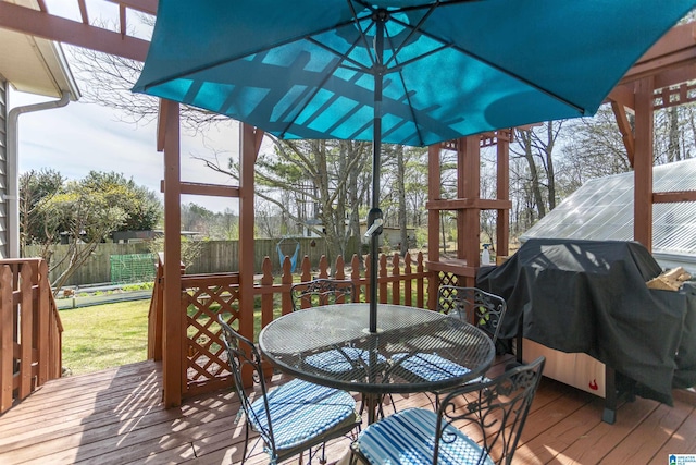 wooden deck with outdoor dining space, fence, and grilling area