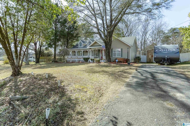 view of front of home featuring driveway, a porch, a front yard, and fence