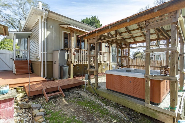 deck featuring a hot tub and fence