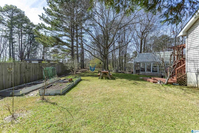 view of yard featuring a garden, an exterior structure, fence, an outdoor structure, and a playground