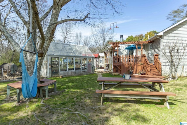 view of jungle gym with a greenhouse, a lawn, a wooden deck, and an outdoor structure