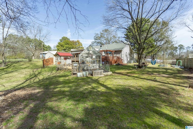 view of yard featuring an outbuilding, a greenhouse, and fence