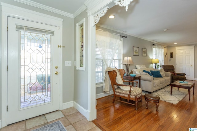 entrance foyer with ornamental molding, light wood-style floors, and baseboards