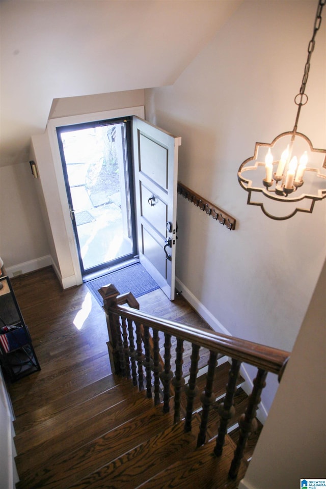 entrance foyer featuring lofted ceiling, wood finished floors, a chandelier, baseboards, and stairs