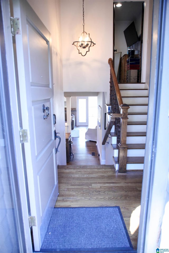 foyer with a notable chandelier, decorative columns, stairs, and wood finished floors