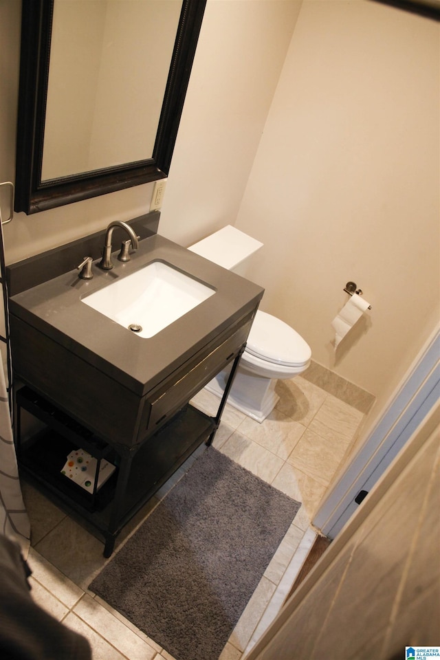 half bathroom with toilet, tile patterned floors, and vanity