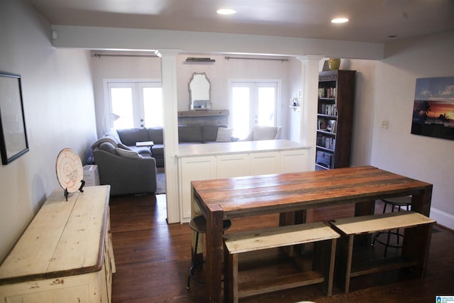 dining space featuring dark wood-type flooring, french doors, and ornate columns