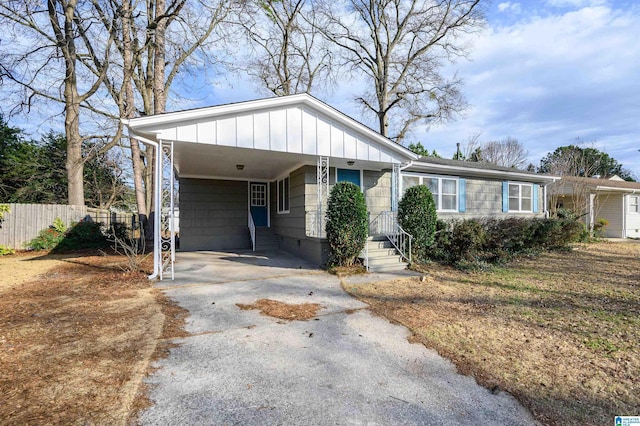 ranch-style home featuring a carport, fence, aphalt driveway, and board and batten siding